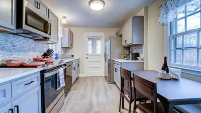 a kitchen with white cabinets and a table with chairs at Family Retreat Near Yale - Stylish Free Wifi in New Haven