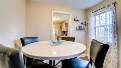 a dining room with a white table and black chairs at Family Retreat Near Yale - Stylish Free Wifi in New Haven