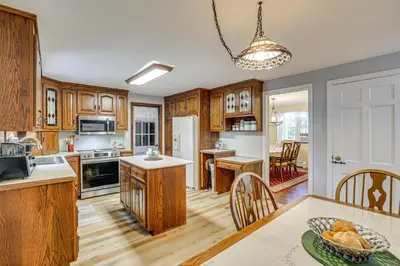 a kitchen with wooden cabinets and a table with a bowl of fruit at Family Getaway in Bristol Near Trails and Parks! in Bristol