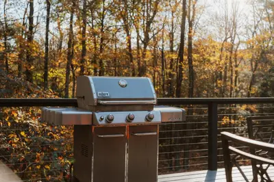 a grill on a deck with a table and chairs at Tuthill Treehouse - Secluded Mountain Cabin with Roof Deck & Fire Pit in Pond Eddy