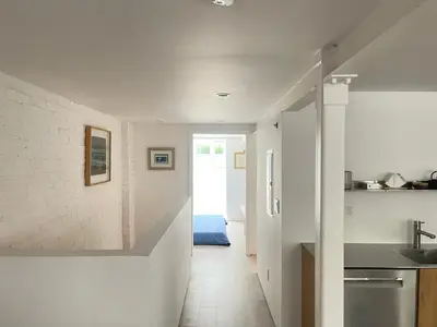 a kitchen with white walls and a hallway with a sink at Williamsburg Design Apartment in Brooklyn