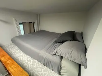 a bed with gray sheets and pillows in a bedroom at Renovated Studio in Union Square in New York