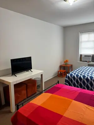 a room with a bed and a desk with a television at Room in New York in Jackson Heights
