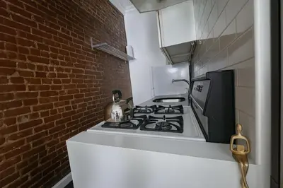a kitchen with a stove and a brick wall at Heavenly Stays in New York