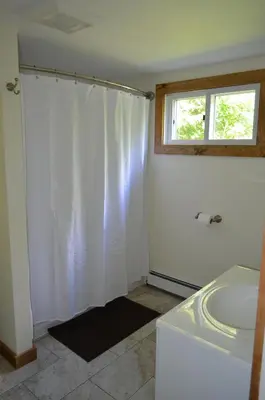 a white bathroom with a tub and a window at Green River Cottage in Guilford