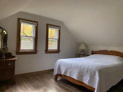 a bedroom with a bed and two windows at Green River Cottage in Guilford