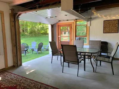 a dining room with a table and chairs on a patio at Green River Cottage in Guilford