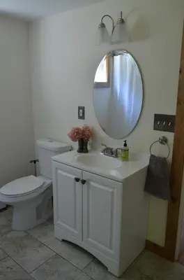 a bathroom with a toilet and a sink with a mirror at Green River Cottage in Guilford