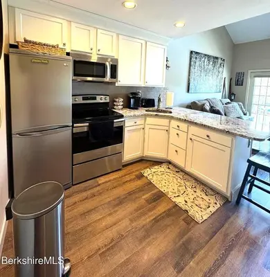 a kitchen with stainless steel appliances and wooden floors at Luxury Jiminy Ski On Off Village Ctr Condo Sleeps4 in Hancock