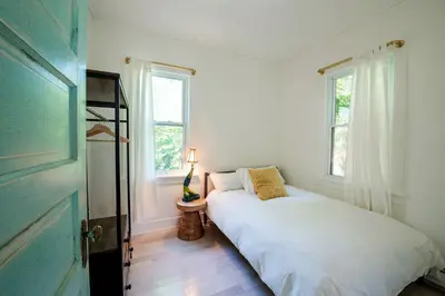 a bedroom with a white bed and two windows at Cozy Cottage on a Private Farm Nestled Among the Southern Catskill Mountains in Woodridge, New York in Woodridge