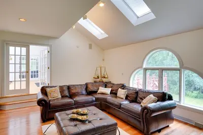 a living room with leather furniture and large windows at Pool Table and Deck Luxury Mansion in Niskayuna! in Niskayuna