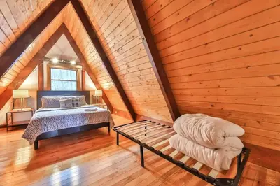 a bedroom with a bed and a bench in a attic at Triangle Tranquility Unique A Frame 6 BR Home in Lanesville