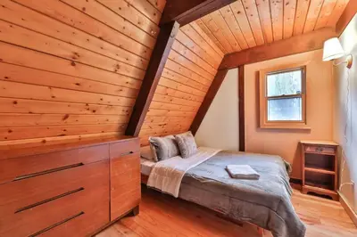 a bedroom with a bed and a wooden wall at Triangle Tranquility Unique A Frame 6 BR Home in Lanesville