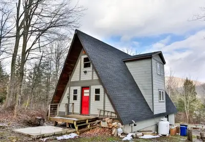 a small house with a gambrel roof with a red door at Triangle Tranquility Unique A Frame 6 BR Home in Lanesville