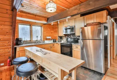 a kitchen with a table and a stainless steel refrigerator at Triangle Tranquility Unique A Frame 6 BR Home in Lanesville