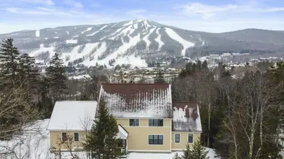a house in the snow with a mountain in the background at Escape to Mountainview Haven Spacious Retreat with Hot Tub at Mount Snow in West Dover