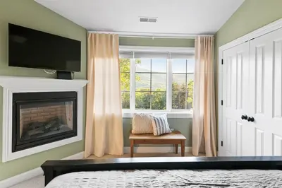 a bedroom with a fireplace and a tv and a window at Escape to Mountainview Haven Spacious Retreat with Hot Tub at Mount Snow in West Dover