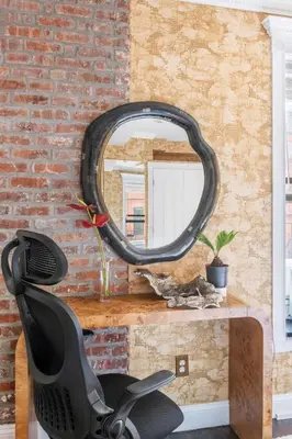 a mirror on a brick wall with a black chair at Studio Nolita in New York