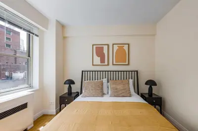 a bedroom with a bed with two night stands and a window at Blueground Murray Hill fitness center nr MetLife NYC-1929 in New York