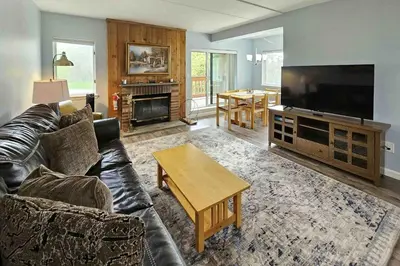 a living room with a black leather couch and a flat screen tv at 5A Mountain Village - Unit A in Dover