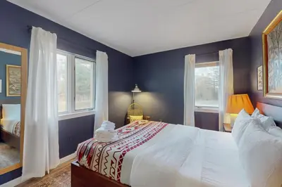 a bedroom with a large bed and two windows at 5A Mountain Village - Unit A in Dover