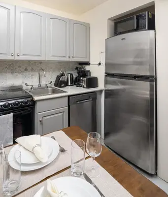 a kitchen with a wooden table with a stainless steel refrigerator at Serene 1B Upper East Side Retreat in New York