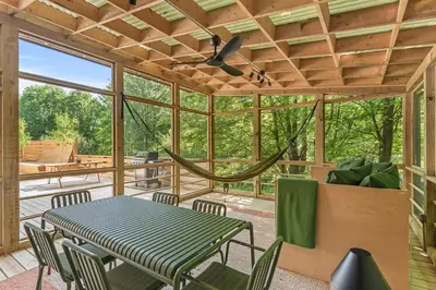 a screened in porch with a table and chairs at Sunlit Airstream in Trees with Expansive Deck Nature Views in De Lancey