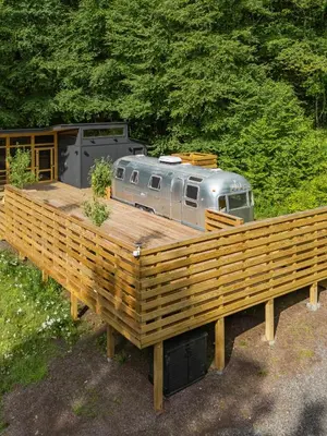 a trailer sitting on top of a wooden deck at Sunlit Airstream in Trees with Expansive Deck Nature Views in De Lancey