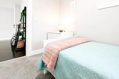 a bedroom with a bed with a pink blanket on it at A brick's throw away to Sally's! in New Haven