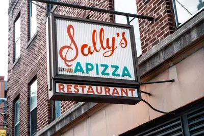 a sign for a restaurant on the side of a building at A brick's throw away to Sally's! in New Haven