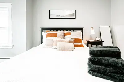 a bedroom with a large white bed with orange and white pillows at A brick's throw away to Sally's! in New Haven