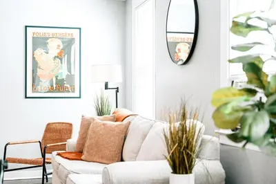 a living room with a white couch and a mirror at A brick's throw away to Sally's! in New Haven