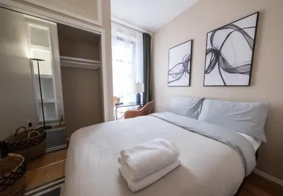 a bedroom with a white bed with two towels on it at Sunlit 2BR Central Park North elevator & laundry in New York