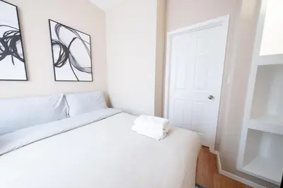 a bedroom with a white bed with two pictures on the wall at Sunlit 2BR Central Park North elevator & laundry in New York