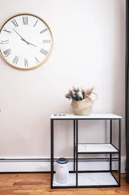 a clock on a wall next to a console table at Sunlit 2BR Central Park North elevator & laundry in New York