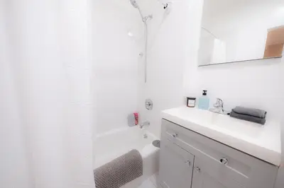 a white bathroom with a sink and a shower at Sunlit 2BR Central Park North elevator & laundry in New York