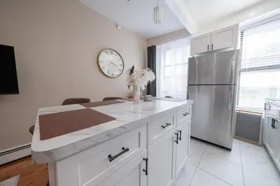 a kitchen with white cabinets and a clock on the wall at Sunlit 2BR Central Park North elevator & laundry in New York