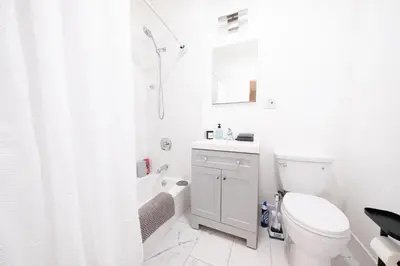 a white bathroom with a toilet and a shower at Sunlit 2BR Central Park North elevator & laundry in New York