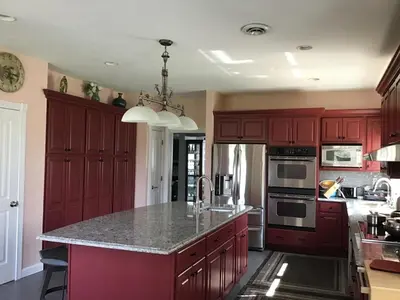 a kitchen with red cabinets and a granite counter top at End of the Rainbow in Ballston Lake