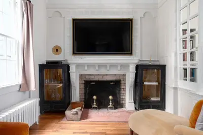 a living room with a fireplace with a television above it at Berkshire Vacation Rentals 1900s Factory Turned Modern Berkshires Retreat in Great Barrington