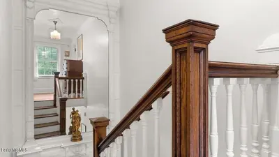 a hallway with a wooden staircase with a mirror at Berkshire Vacation Rentals 1900s Factory Turned Modern Berkshires Retreat in Great Barrington