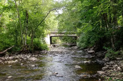 a river with a bridge in the middle at Berkshire Vacation Rentals 1900s Factory Turned Modern Berkshires Retreat in Great Barrington