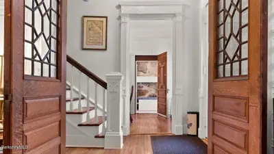 a hallway with white walls and wooden doors and stairs at Berkshire Vacation Rentals 1900s Factory Turned Modern Berkshires Retreat in Great Barrington