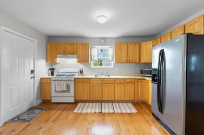 a kitchen with wooden cabinets and a stainless steel refrigerator at Near YALE - Beautiful Waterfront Townhouse in New Haven in New Haven