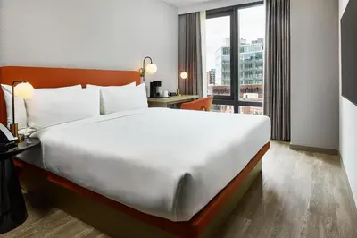 a large bed in a hotel room with a large window at The George Manhattan, Tapestry Collection By Hilton in New York