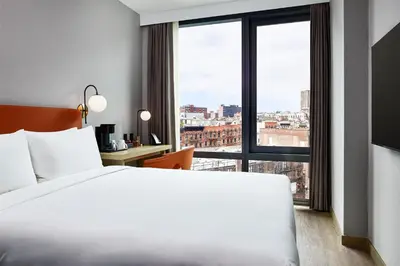 a hotel room with a bed and a large window at The George Manhattan, Tapestry Collection By Hilton in New York