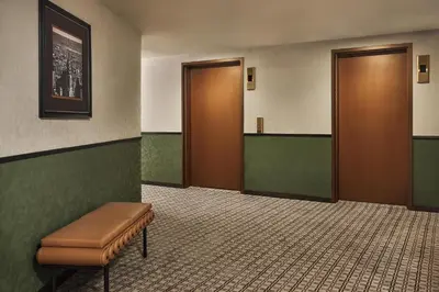 a waiting room with two brown doors and a bench at The George Manhattan, Tapestry Collection By Hilton in New York