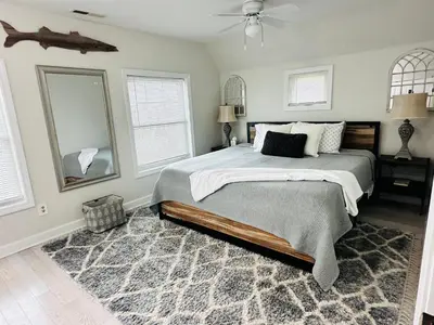 a bedroom with a bed and a fan and windows at coastal and cozy beach stay, pet friendly in Milford