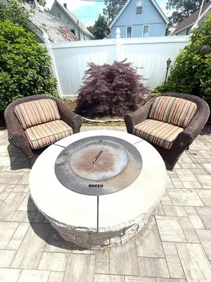 two chairs and a table with a clock on a patio at coastal and cozy beach stay, pet friendly in Milford