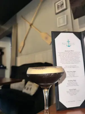 a drink in a martini glass next to a menu at coastal and cozy beach stay, pet friendly in Milford